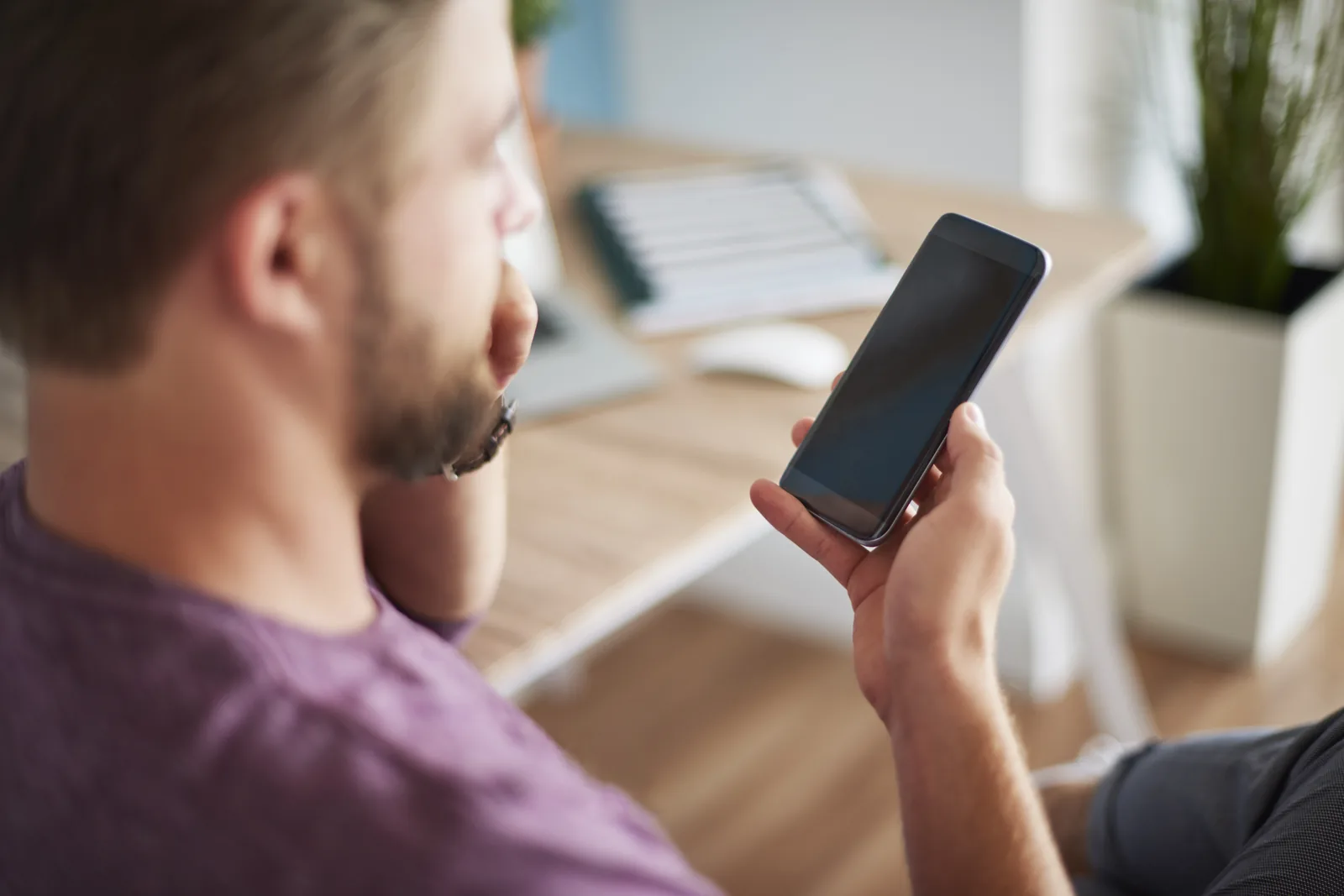 Чоловік вивчає підозріле повідомлення на смартфоні